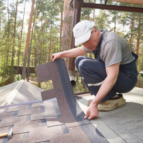 Roofer installing asphalt shingles on roof
