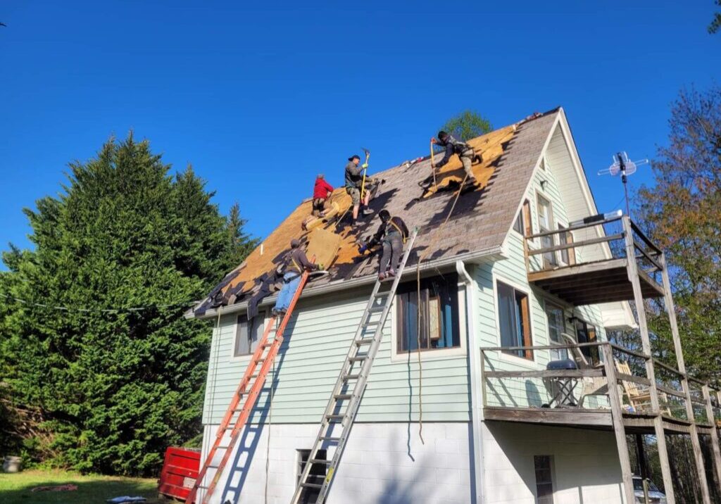 Workers repairing a residential roof under a clear blue sky.